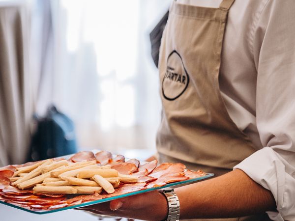 Croquetas gourmet servidas sobre una base de legumbres en evento de catering de Grupo Tartar
